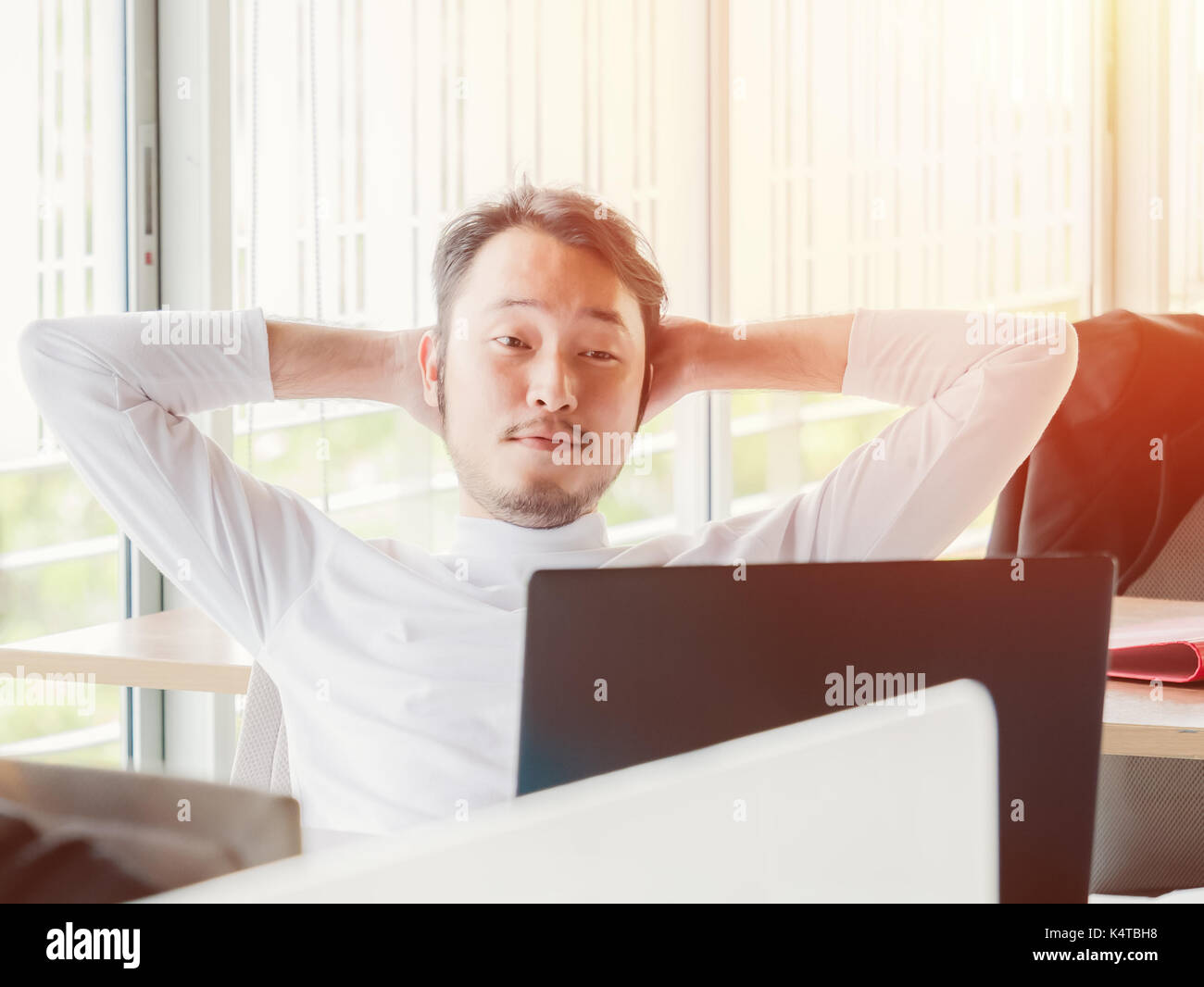 Relaxed casual young man working on laptop in office Stock Photo