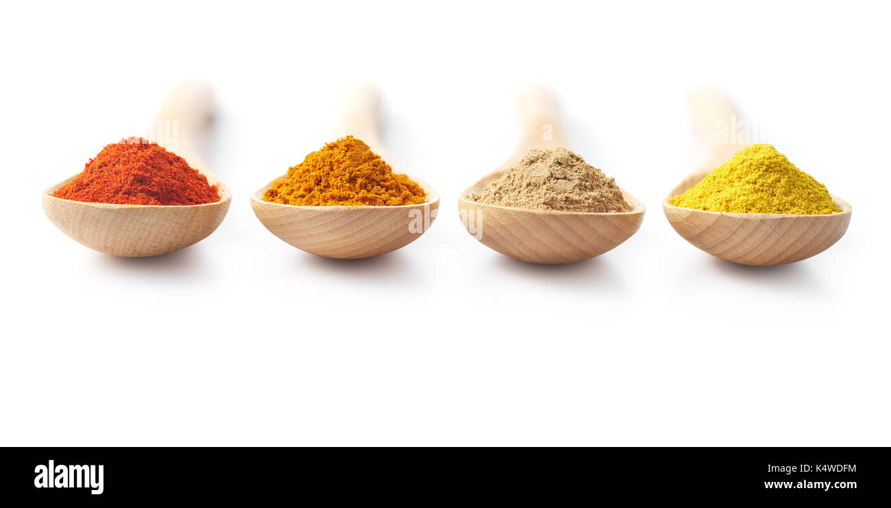 Wooden spoon filled with spice powders on white background Stock Photo