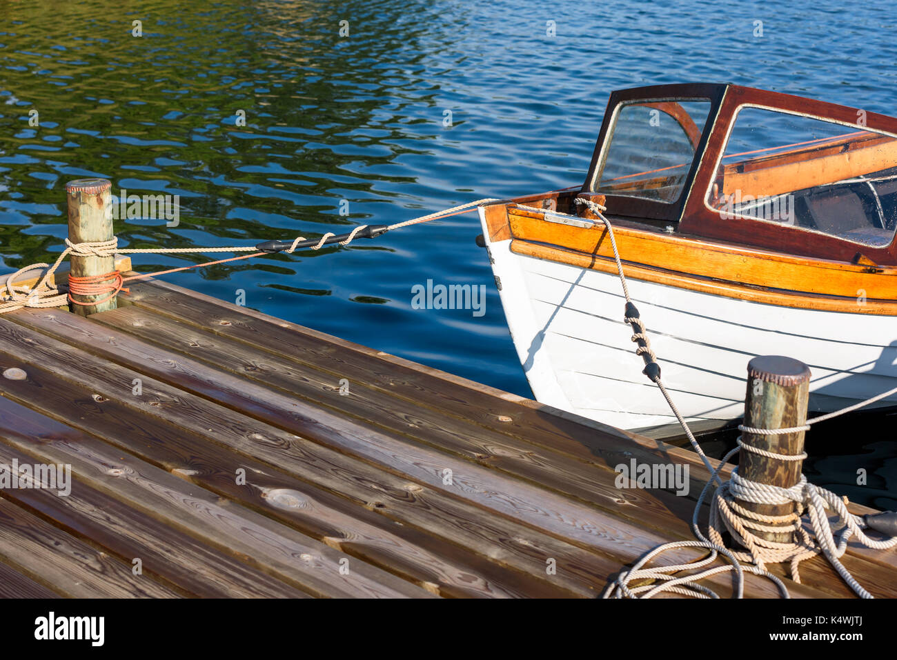 Front of vintage motorboat tied to a pier in calm water. Stock Photo