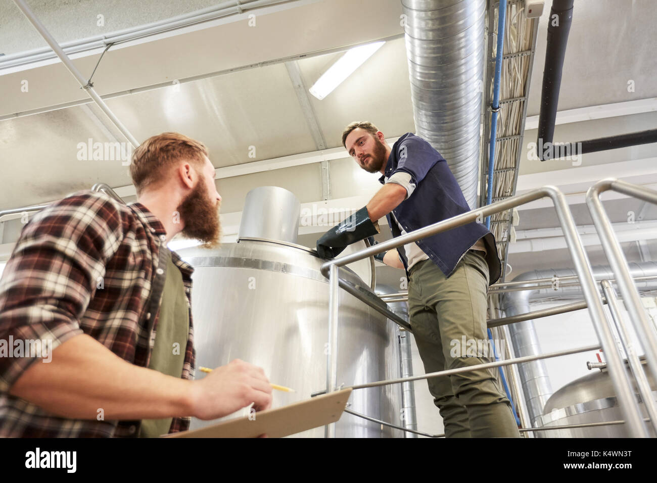 men with clipboard at brewery or beer plant kettle Stock Photo
