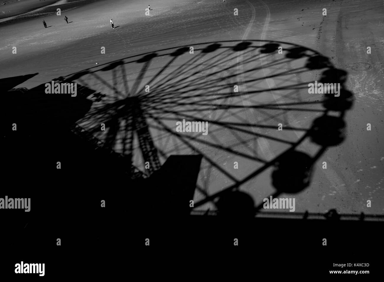 BLACKPOOL - AUGUST 31: The Ferris Wheel on Blackpool's Central Pier creates a shadow on the beach as people walk on the coastline. Stock Photo