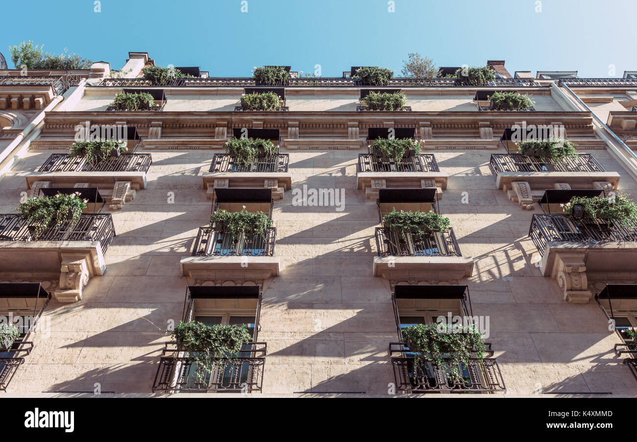 Looking up at an apartment building in Paris in the early morning. Rows of balconies with house plants. Stock Photo