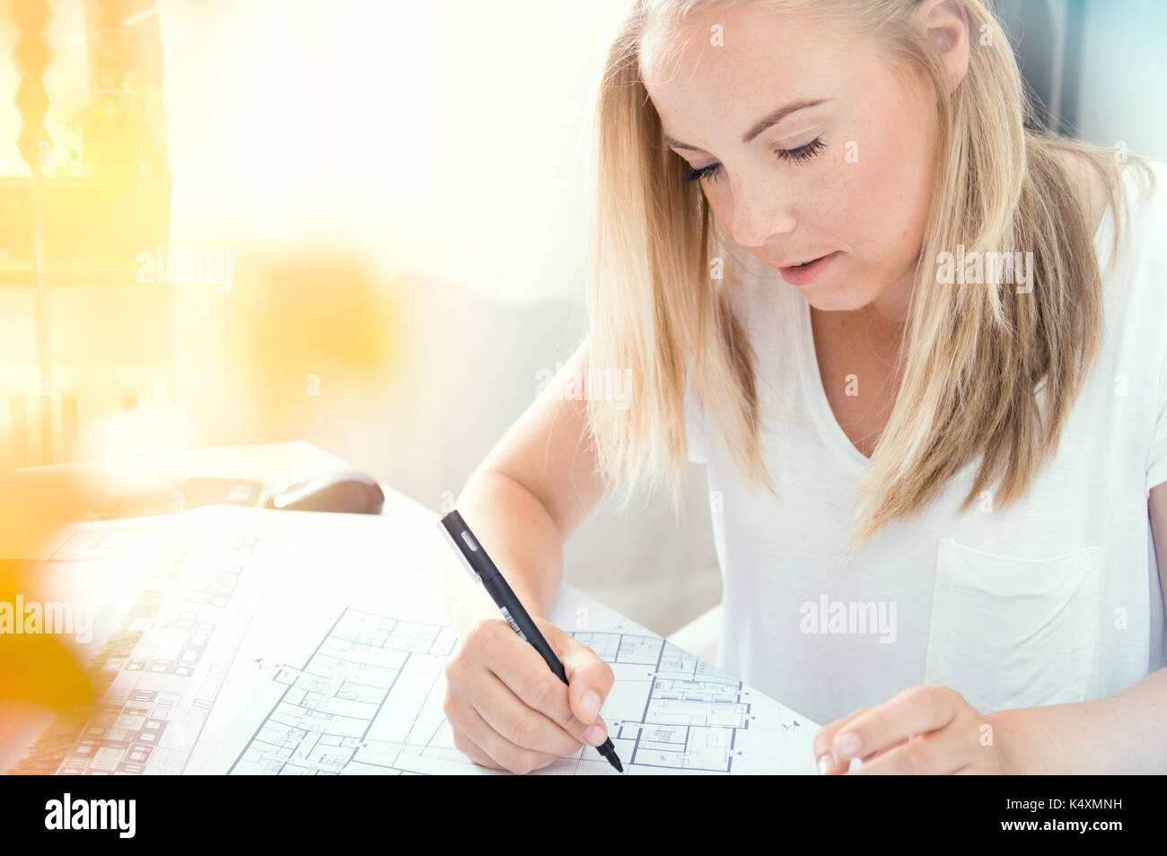 Young blonde architect is making professional architectural plan Stock Photo