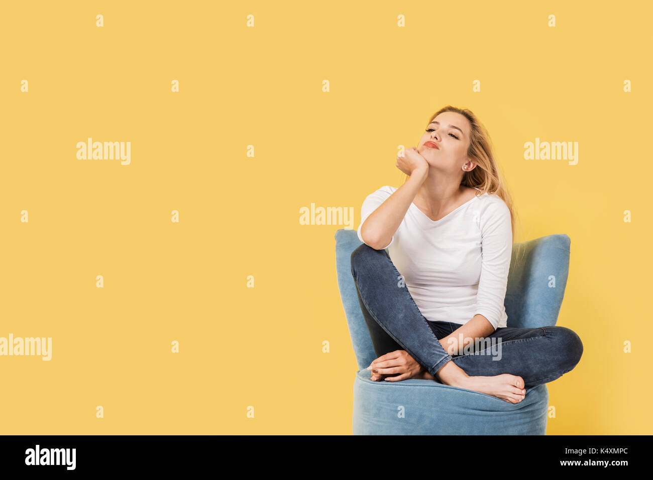 Young blonde woman on chair is bored. Picture includes copy space Stock Photo