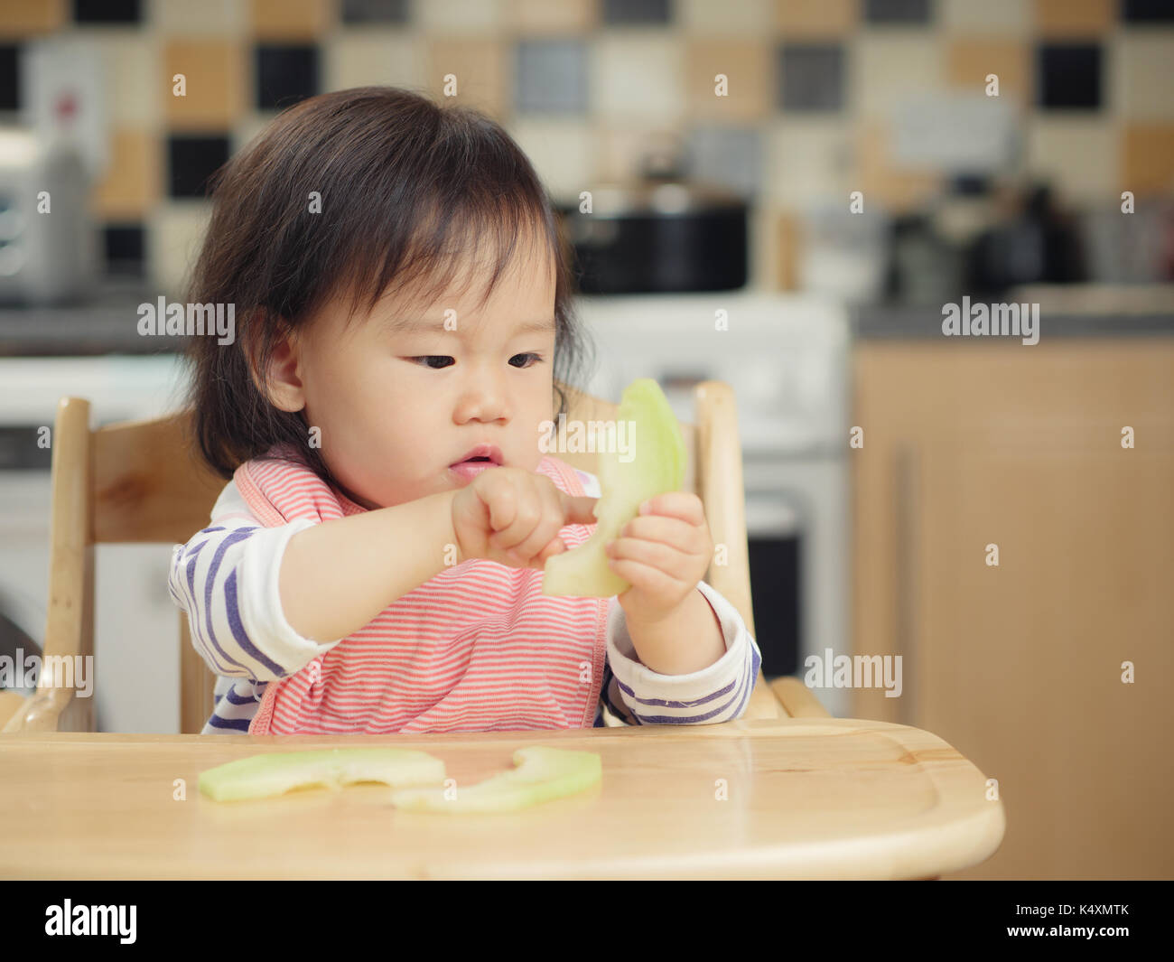 baby girl eating melon at home Stock Photo - Alamy