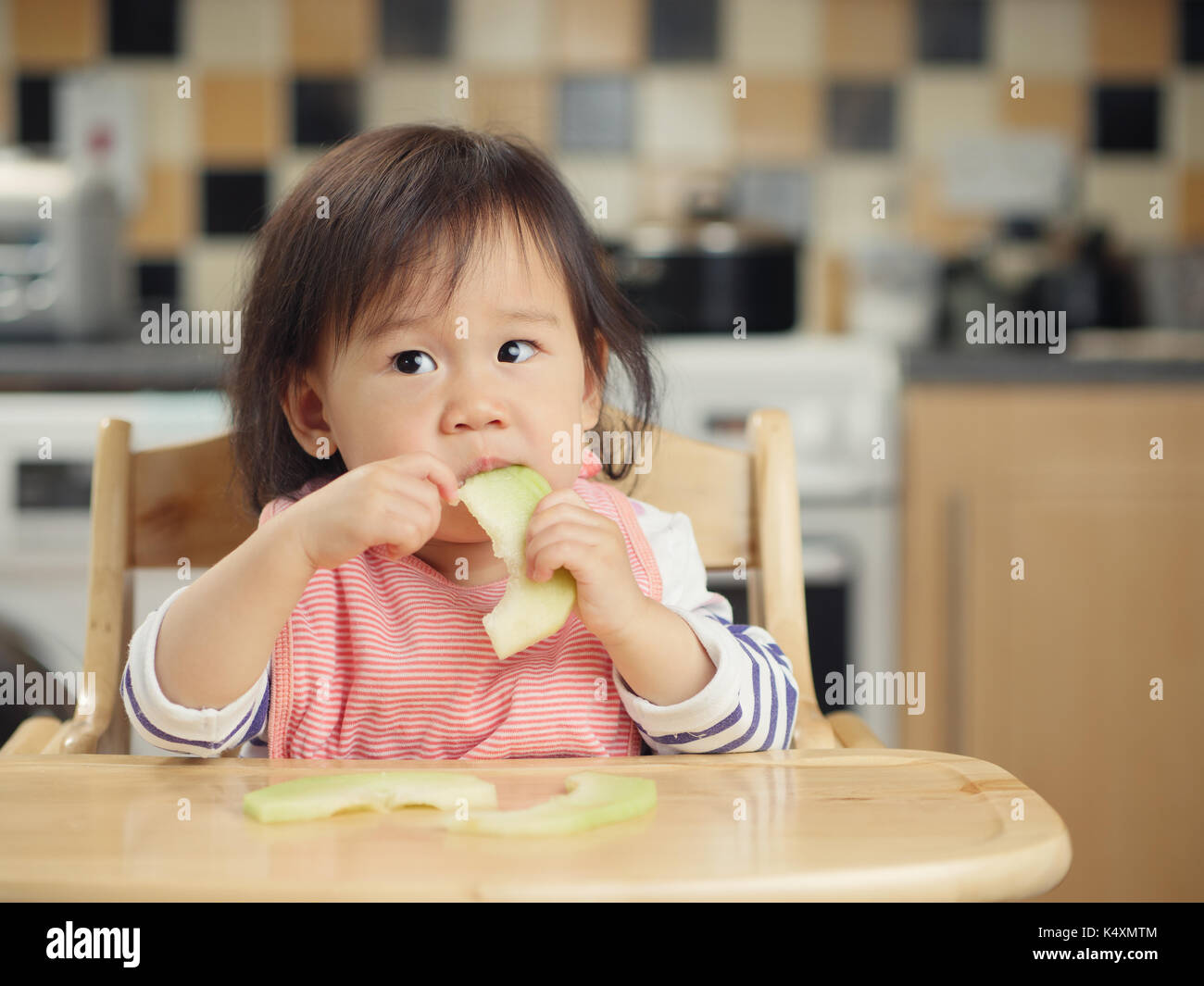 baby girl eating melon at home Stock Photo - Alamy
