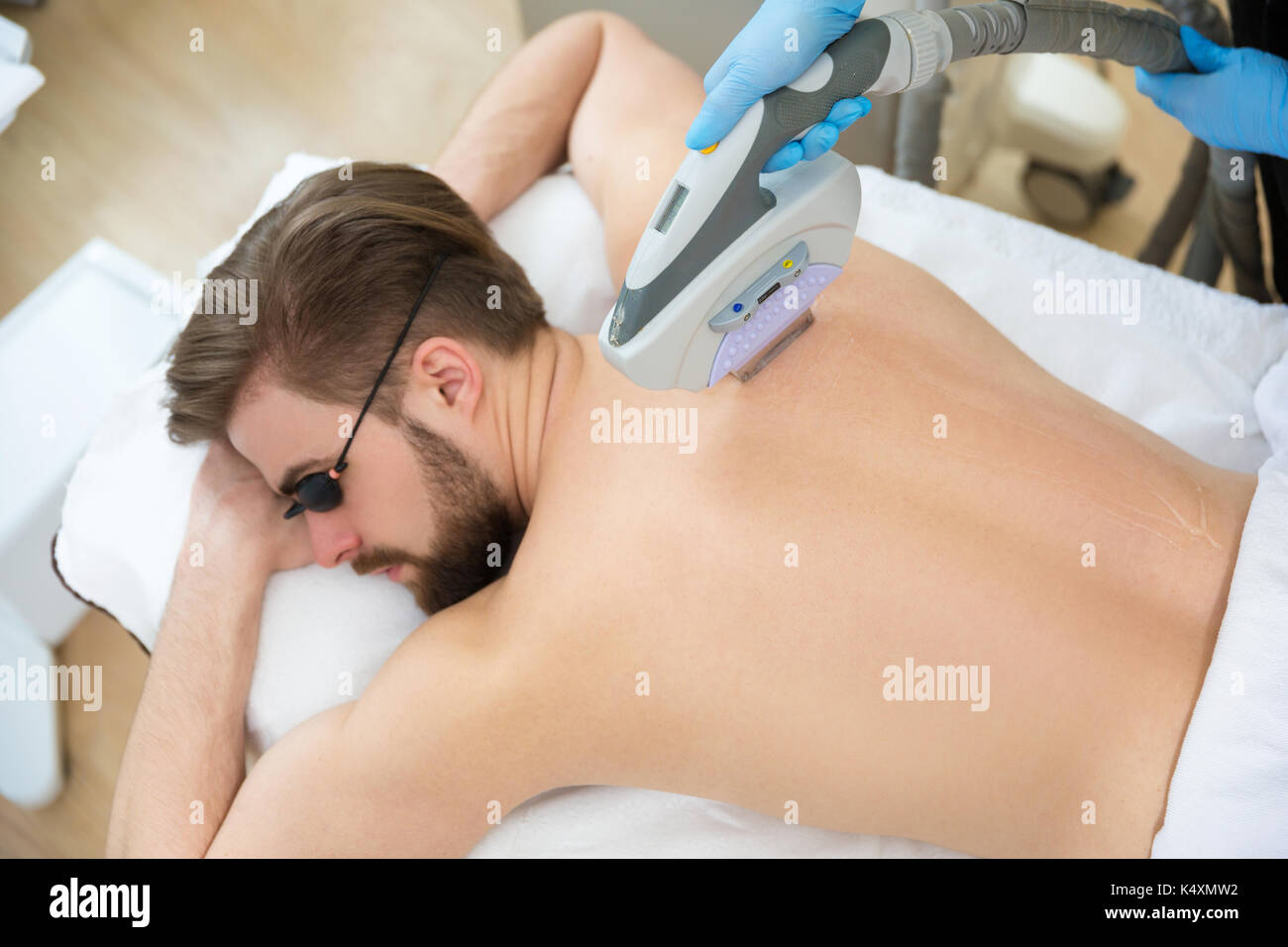 Men Lying At Beautician S During Laser Back Hair Removal Therapy