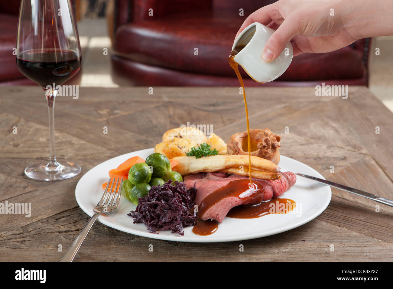 Roast beef dinner with gravy on a plate on a wooden table Stock Photo