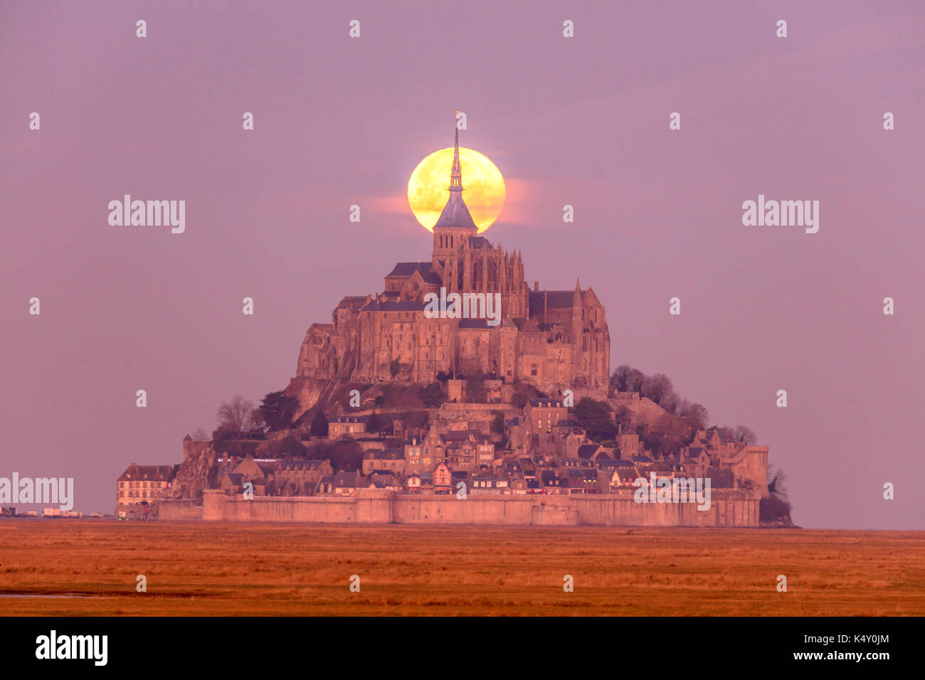Mont Saint-Michel (Saint Michael's Mount), Normandy, north-western France: the moon behind the mount at sunrise Stock Photo