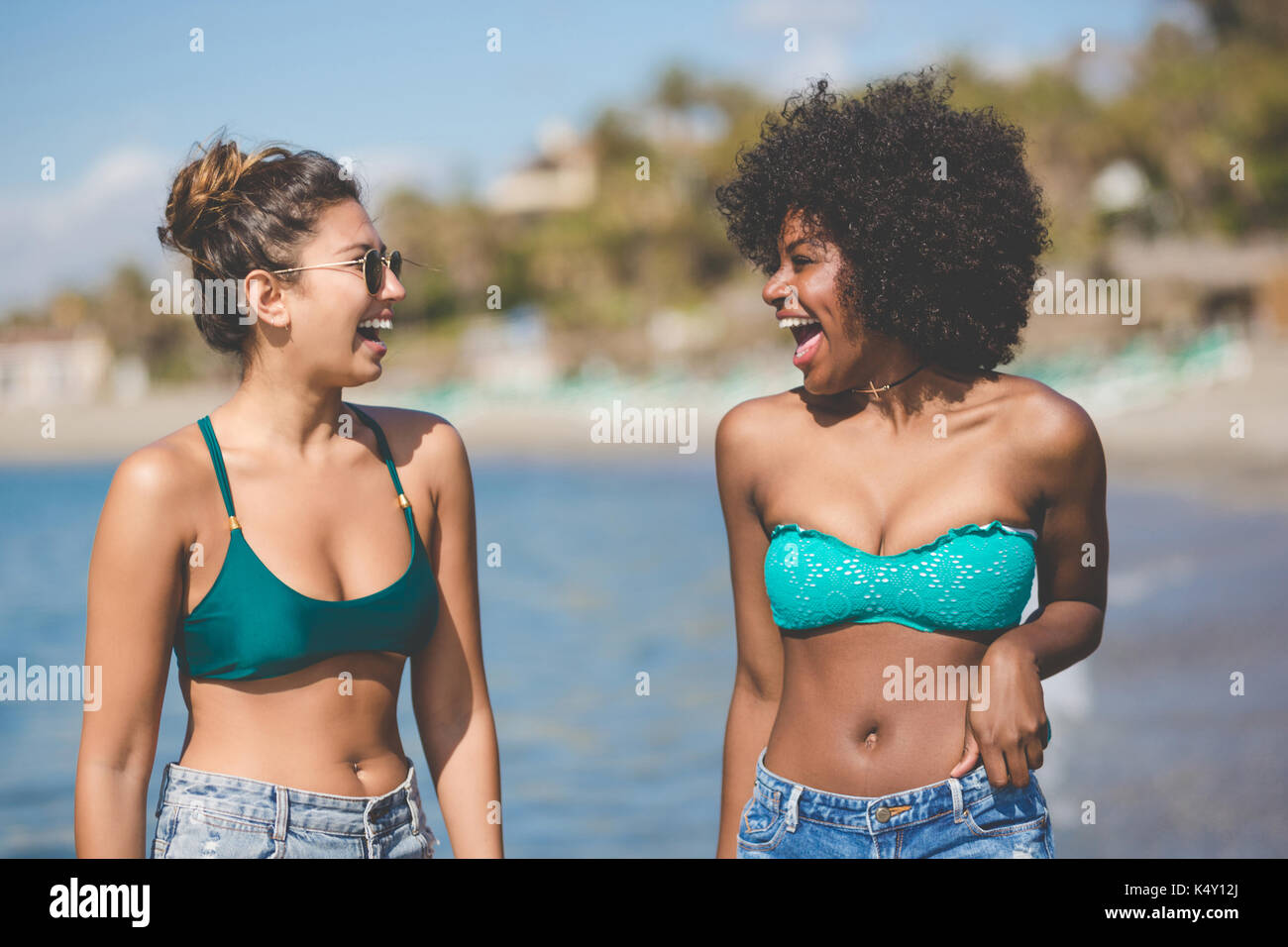 Portrait of two pretty female friends at seaside laughing Stock Photo