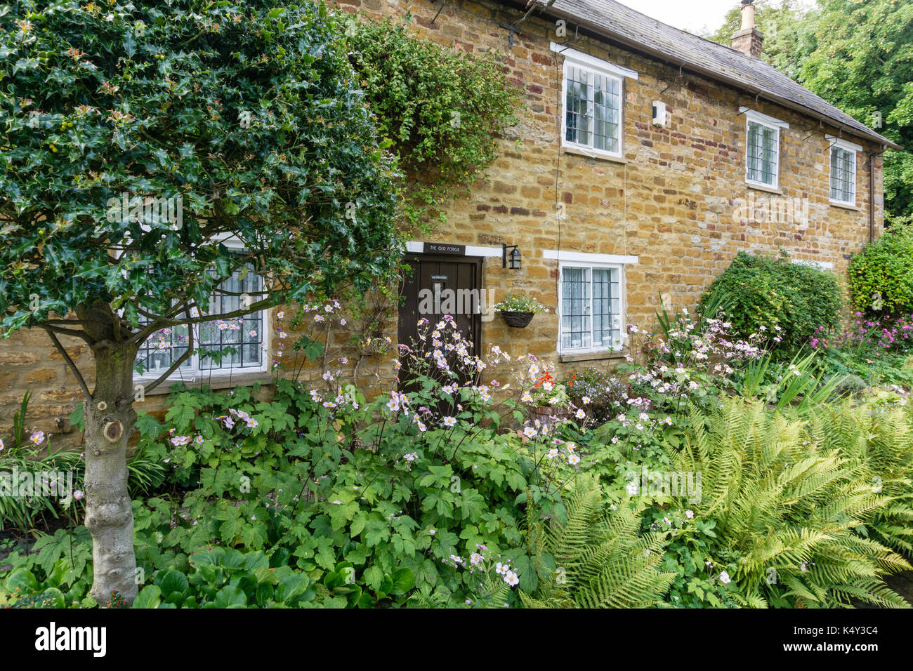 Row of pretty terraced cottages bordering a stream in the village of Dallington, Northampton, UK Stock Photo