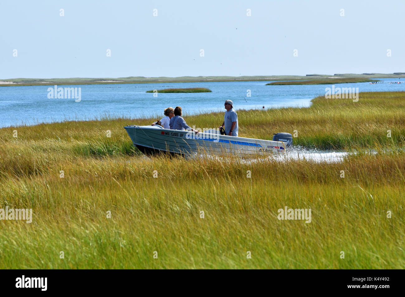 A motorboat makes its way though a salt marsh at Fort Hill in the Cape Cod National Seashore Stock Photo