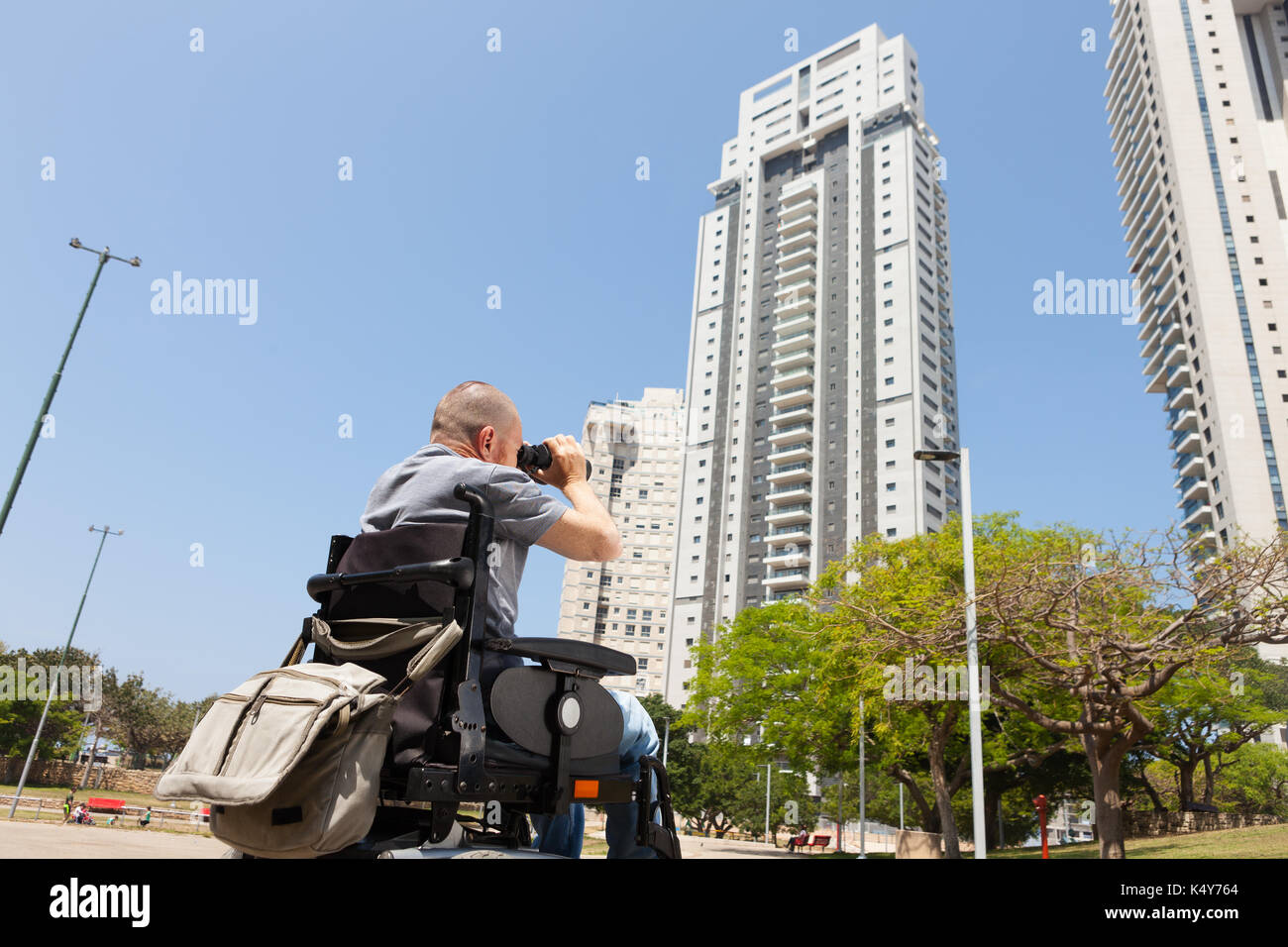 A disabled man in a wheelchair looks through binoculars Stock Photo