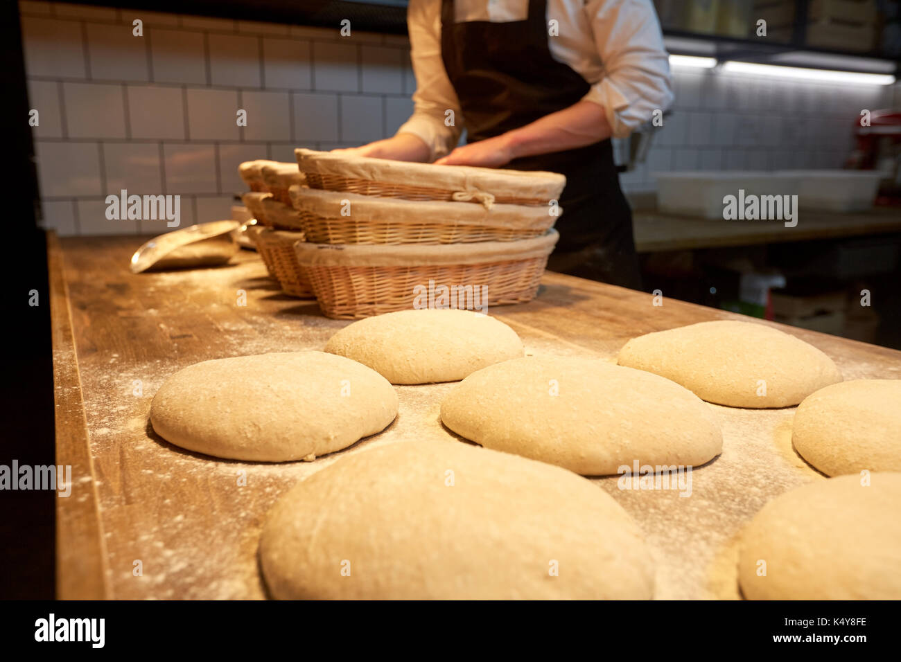 baker with baskets for dough rising at bakery Stock Photo Alamy