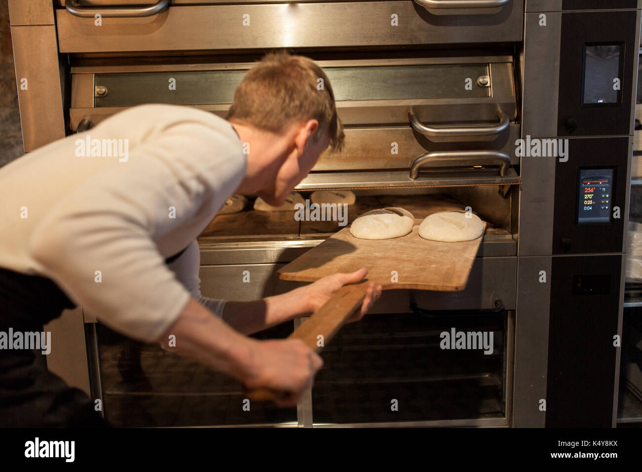 baker putting dough into bread oven at bakery Stock Photo 157951470