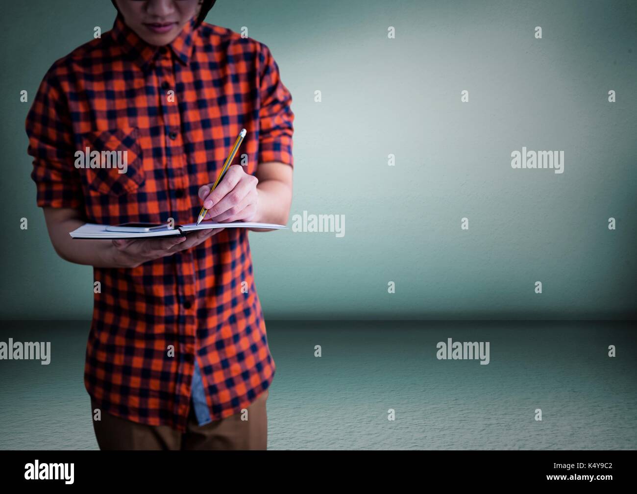 Digital composite of Millennial man mid section writing in notepad ...