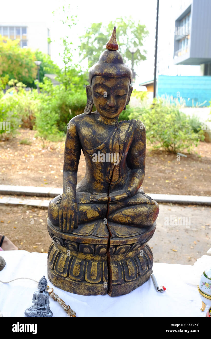 A cracked antique statue of Buddha on sale on a market stall in the Marche aux Puces, the flea market, at Porte de Vanves in Paris Stock Photo