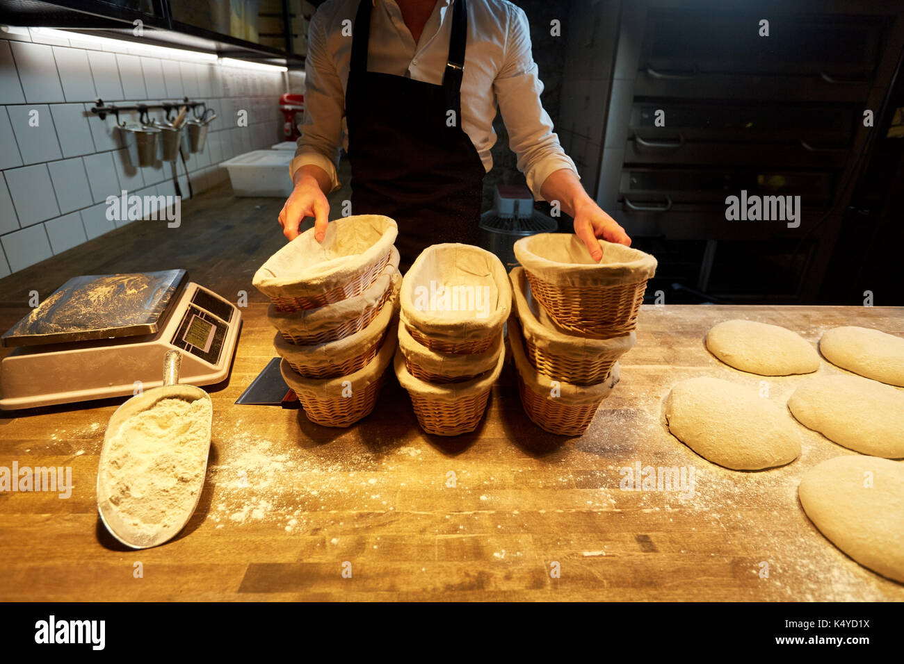 baker with baskets for bread dough at bakery Stock Photo Alamy