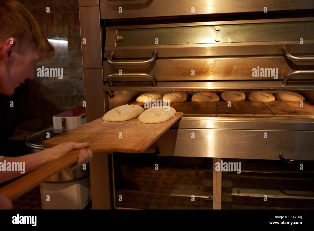 baker putting dough into bread oven at bakery Stock Photo Alamy