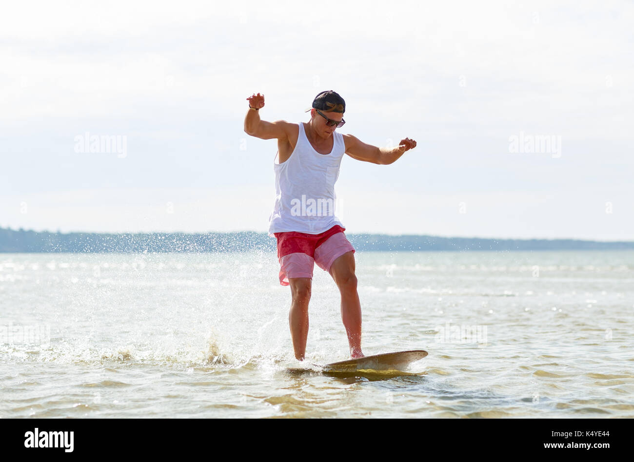 young man riding on skimboard on summer beach Stock Photo