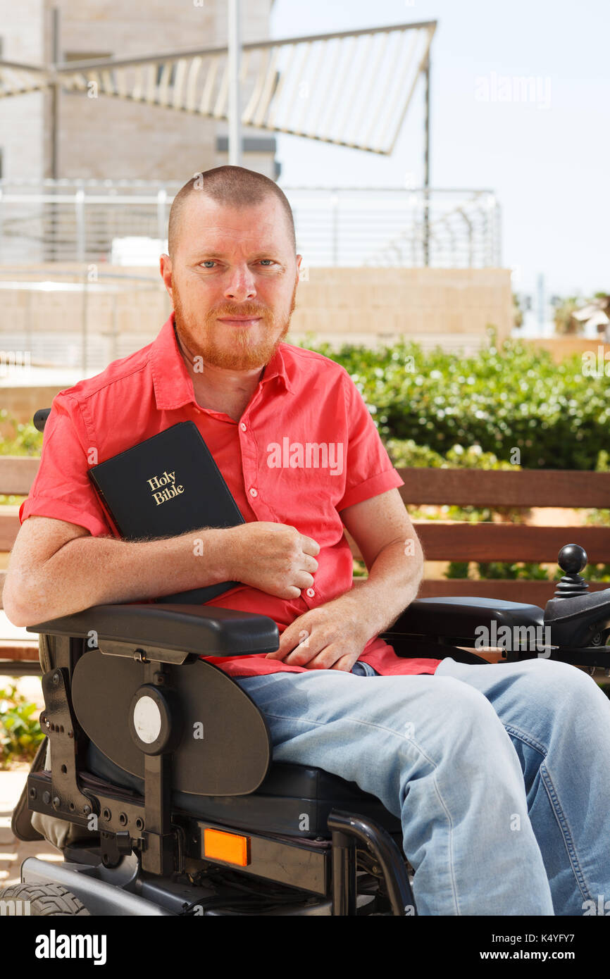 Holy Bible in the hands of disabled man on the wheelchair. Stock Photo