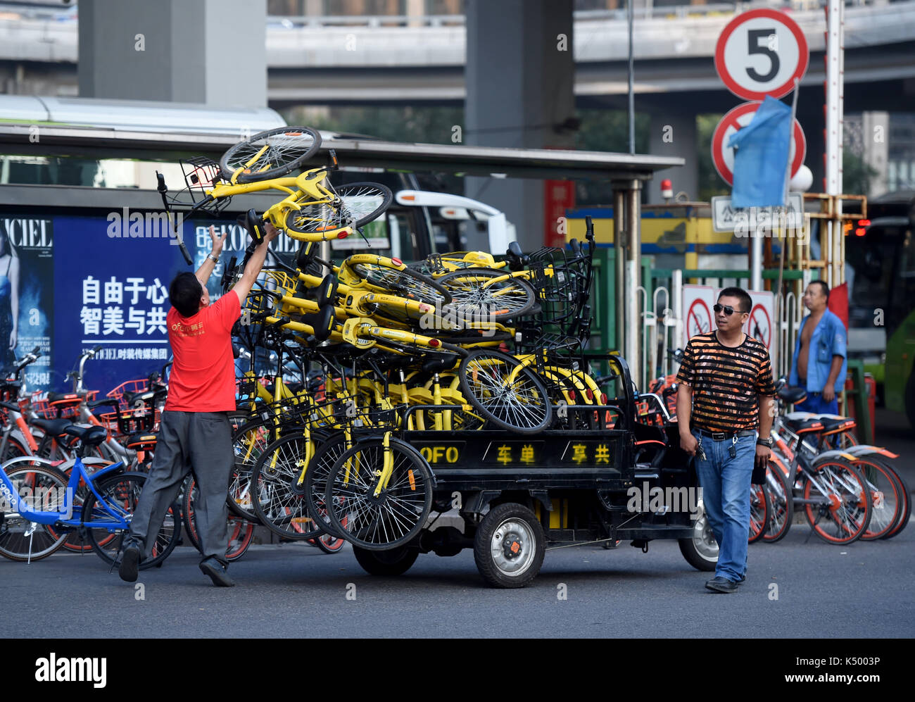 (170908) -- BEIJING, Sept. 8, 2017 (Xinhua) -- A working staff arranges the shared bikes parked under the Guomao Bridge in Beijing, capital of China, Sept. 7, 2017. Beijing will ban the new addition of shared bikes in the city, local authorities announced Thursday. There are 2.35 million shared bikes from 15 companies on the streets of the national capital, according to a spokesperson with the Beijing Municipal Commission of Transport. Shared bikes, the number of which surged in Beijing in the past year, have led to haphazard parking and obstructions in crowded areas such as subway entrances Stock Photo