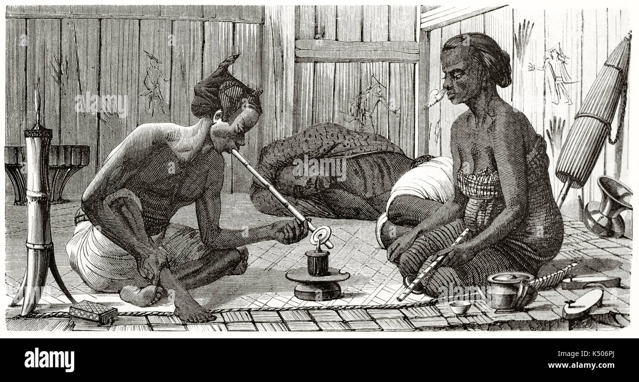 Ancient illustration of two Malaysian smoking opium on a carpet in a wodden house while a third one lying down under drug effect. By Boulanger published on Le Tour du Monde Paris 1862 Stock Photo