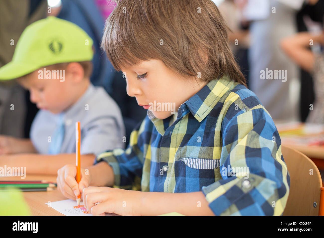 Young first grade student sitting at desk on his first day at school in the classroom Stock Photo