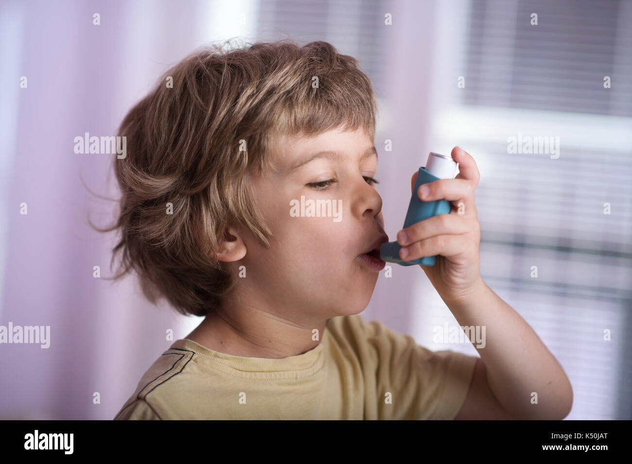 Boy using asthma inhaler to treat inflammatory disease, wheezing, coughing, chest tightness and shortness of breath. Allergy treating concept. Stock Photo