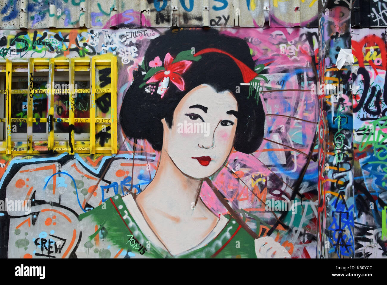 ATHENS, GREECE - DECEMBER 10, 2015: Geisha graffiti traditional japanese female figure with parasol on colorful spray painted wall. Urban street art. Stock Photo