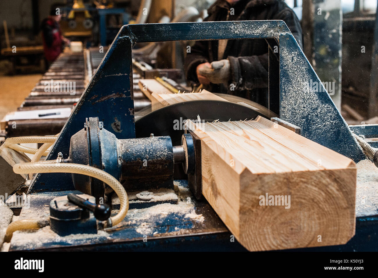 Circular Saw. Carpenter Using Circular Saw for wood. Woodworking machine sawing wooden beam. in progress with another view Stock Photo