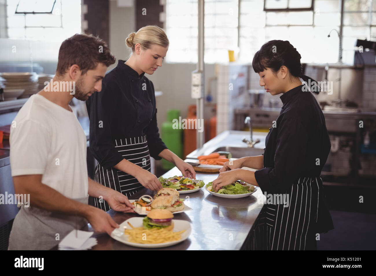 Young wait staff with fresh food in plates on kitchen counter at coffee