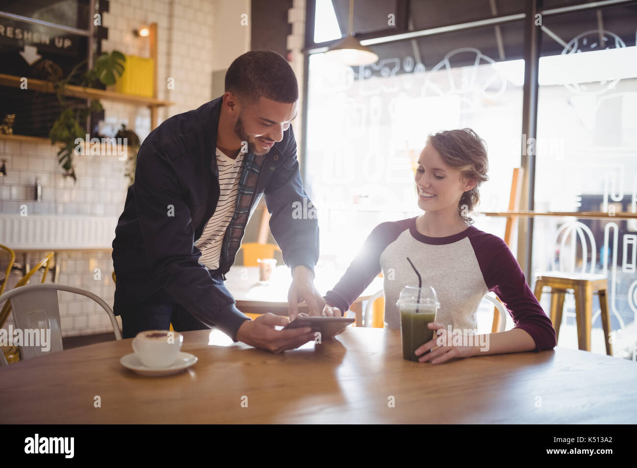 Young man showing digital tablet to woman at coffee shop Stock Photo