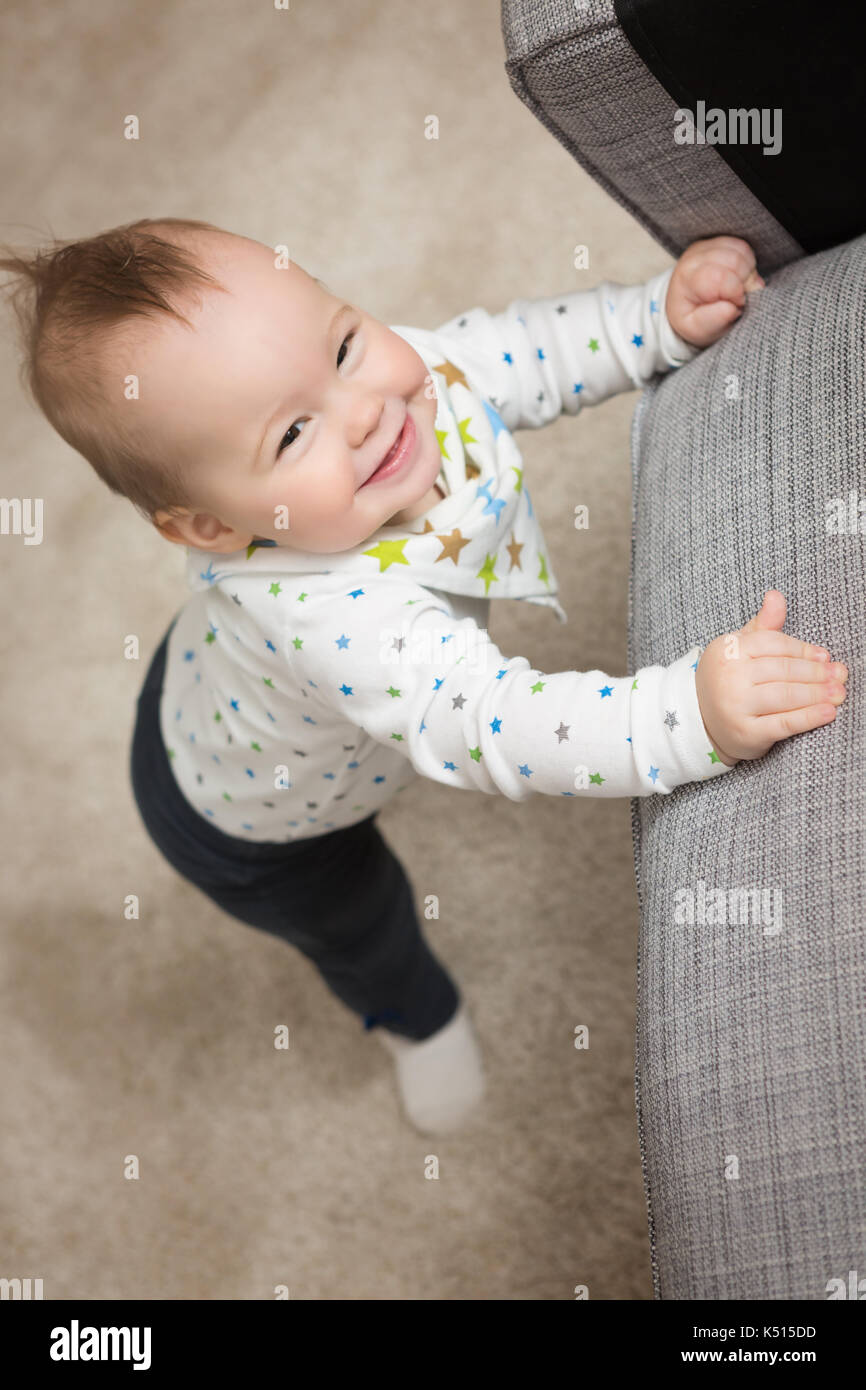 Nine months old baby girl standing on her feet in an effort to climb up