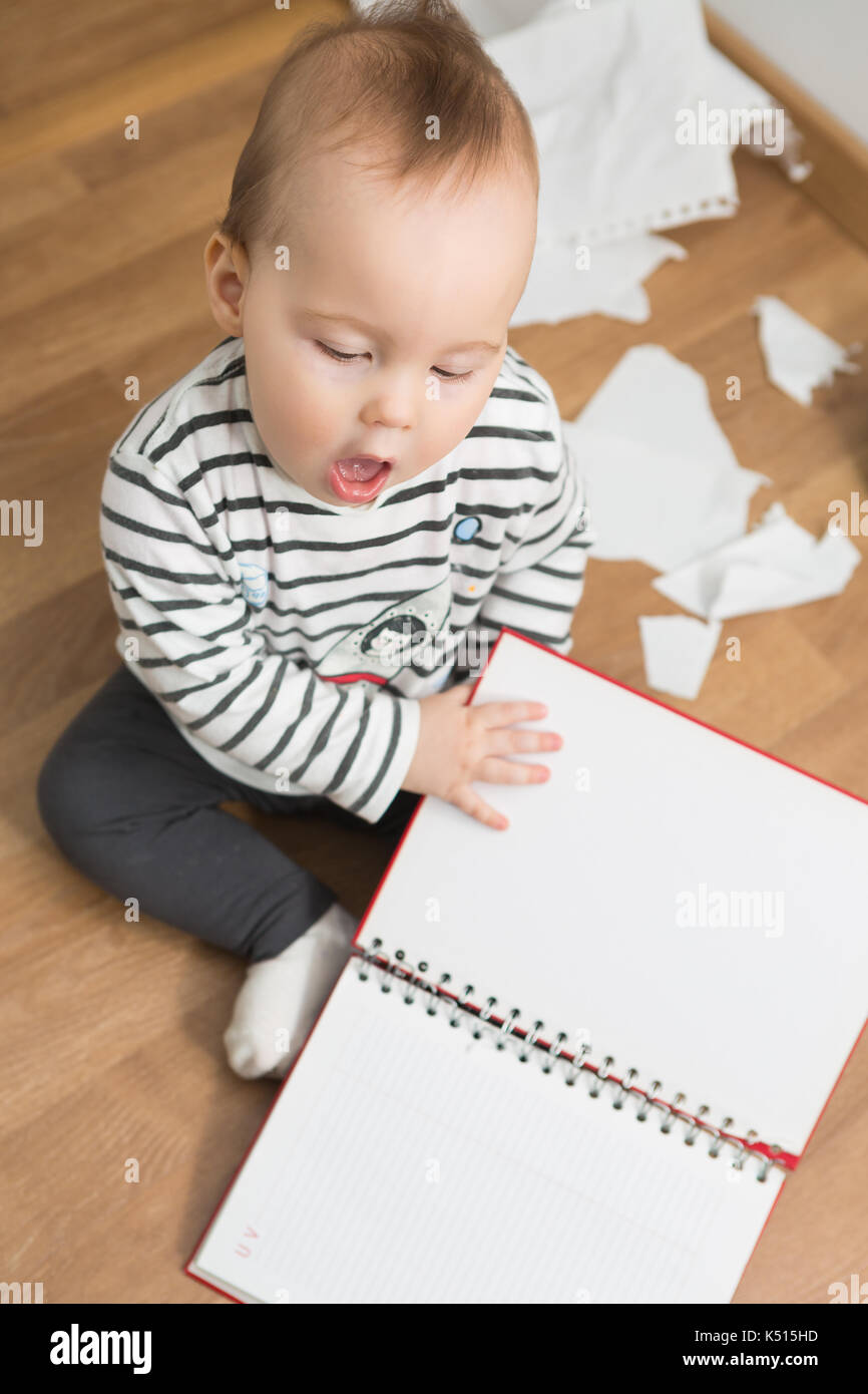 Ten months old baby girl playing with papers and paper folder on the