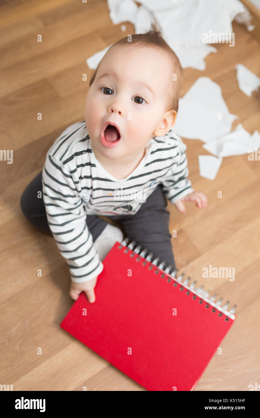 Ten months old baby girl playing with papers and paper folder on the