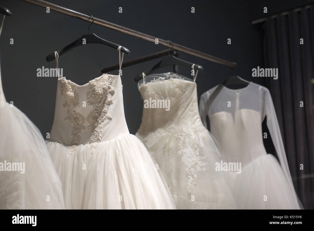 Selection of handmade white wedding gowns hanging on a rail in a ...