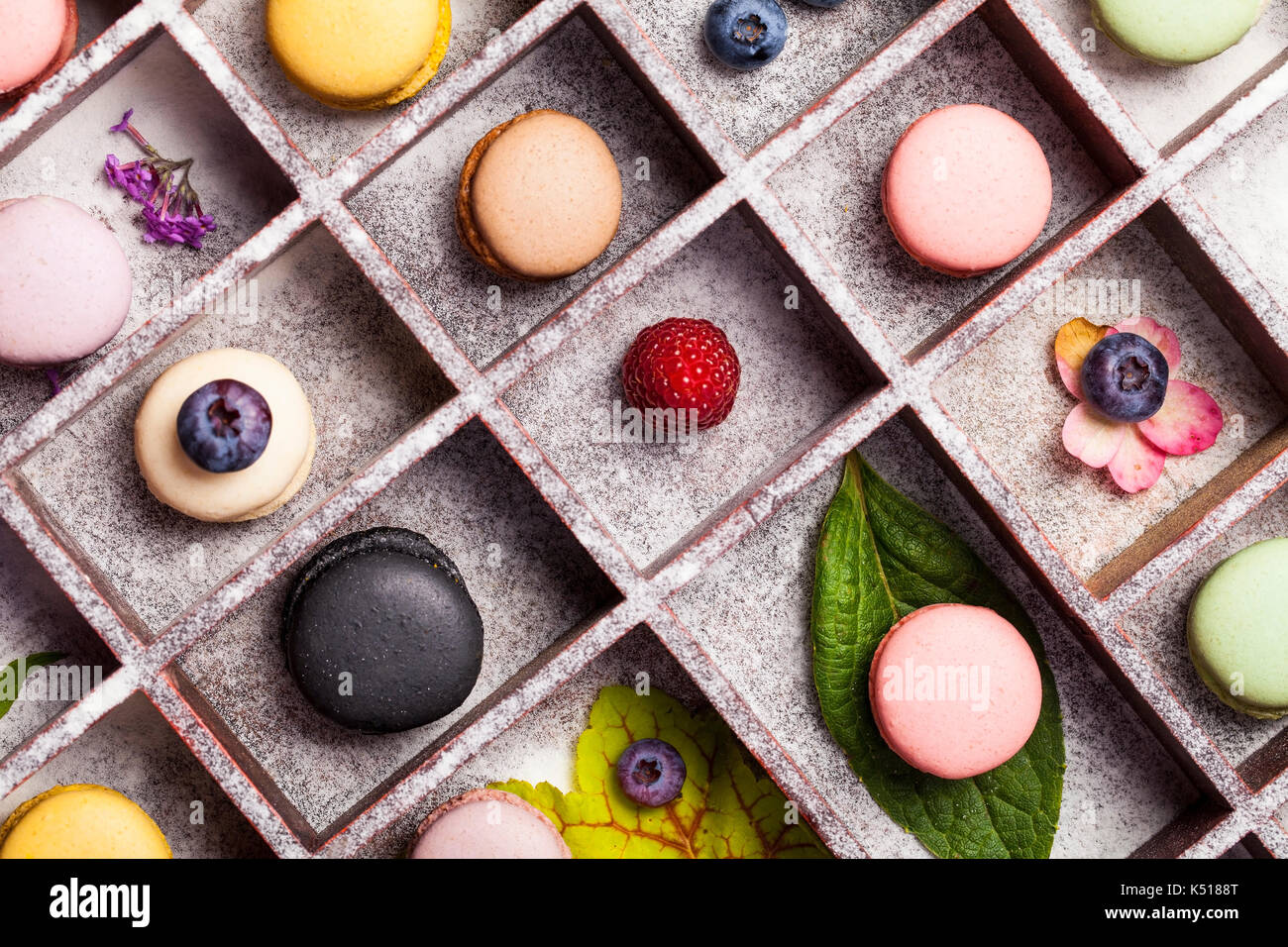 Variety of colorful french sweet dessert - makaron ( les macarons) with autumn flowers and berries. Stock Photo