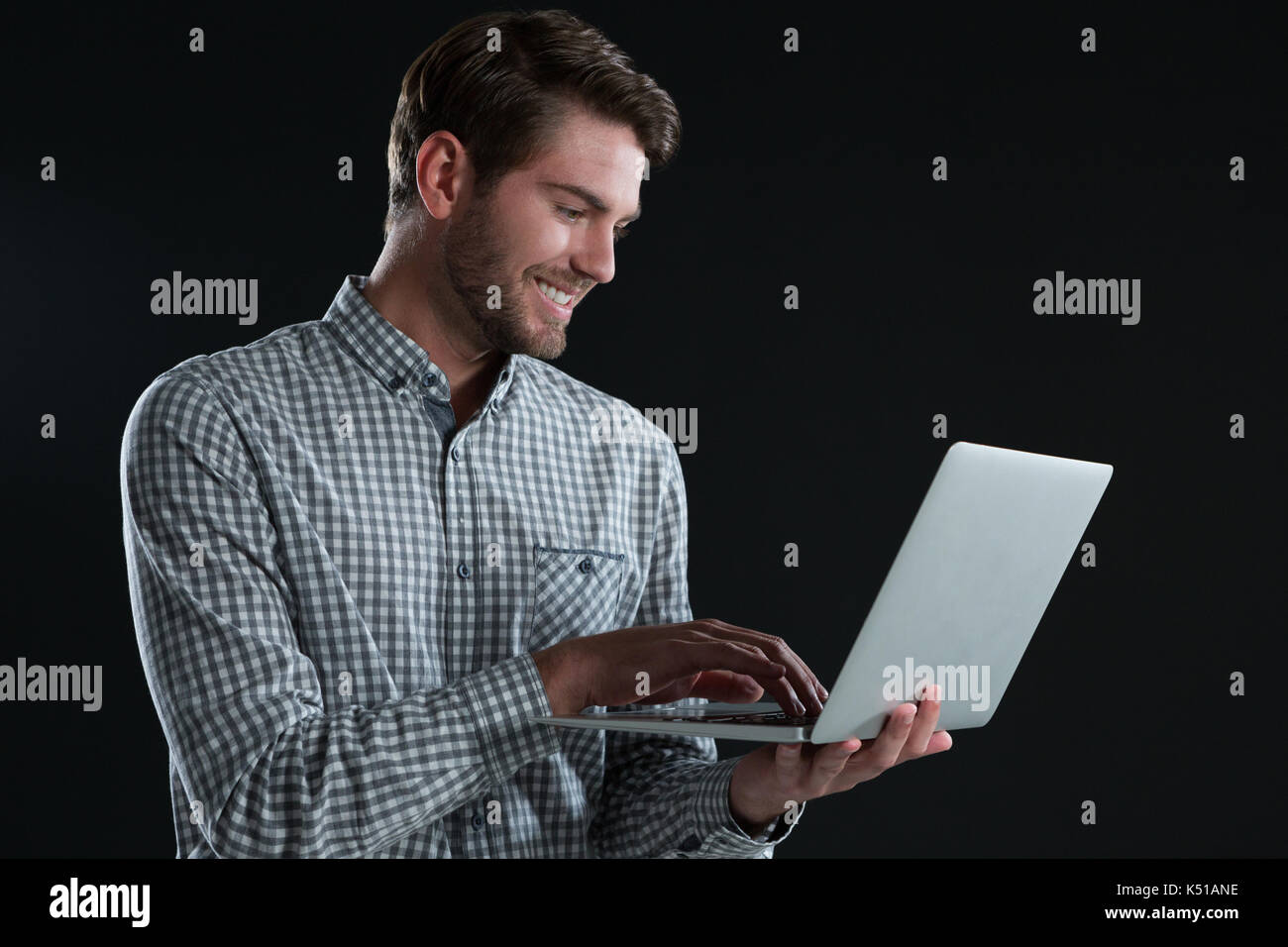 Man holding laptop against black hi-res stock photography and images ...