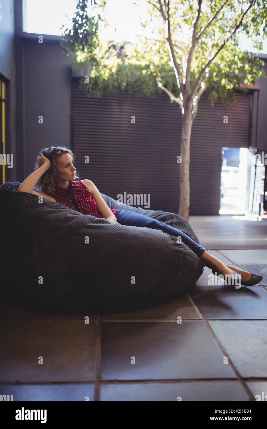 Full length of young woman relaxing on bean bag against wall Stock ...