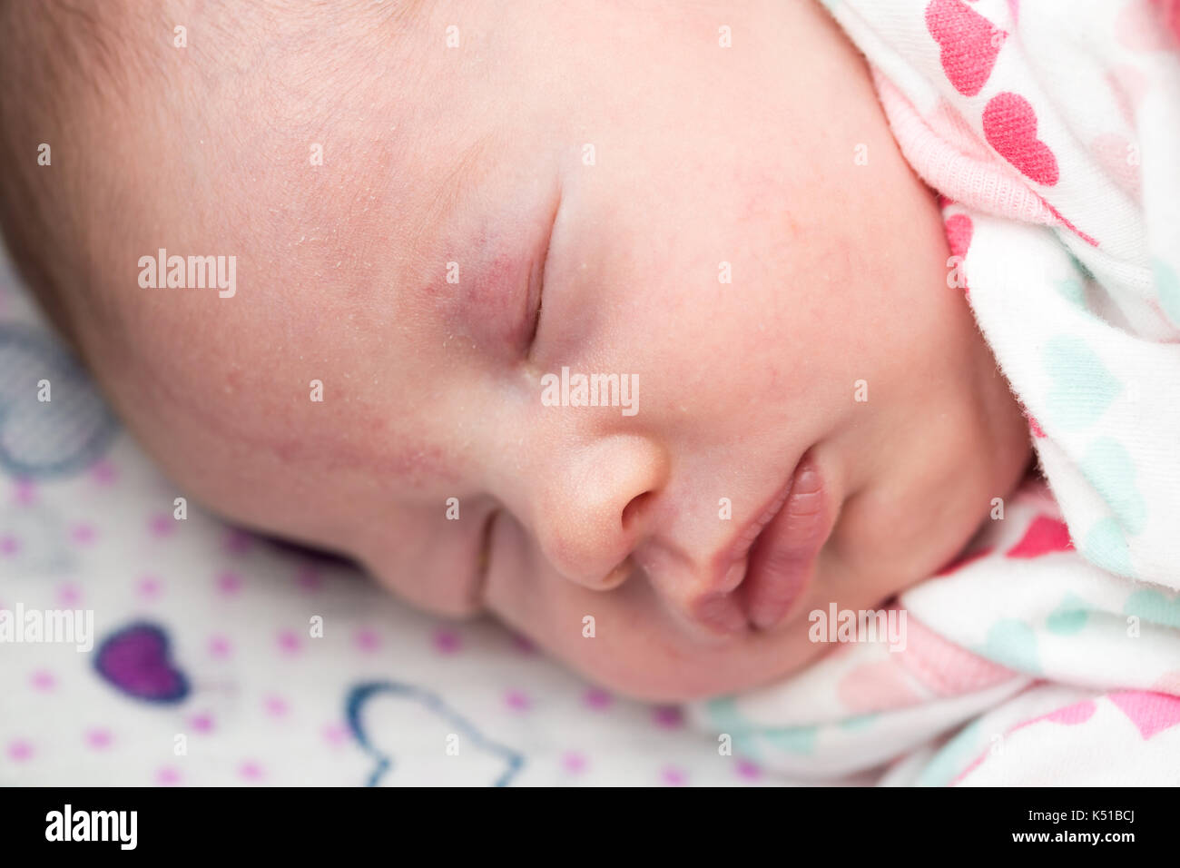 Closeup of a newborn baby sleeping in the crib, stork bite on forehead and eyelid Stock Photo