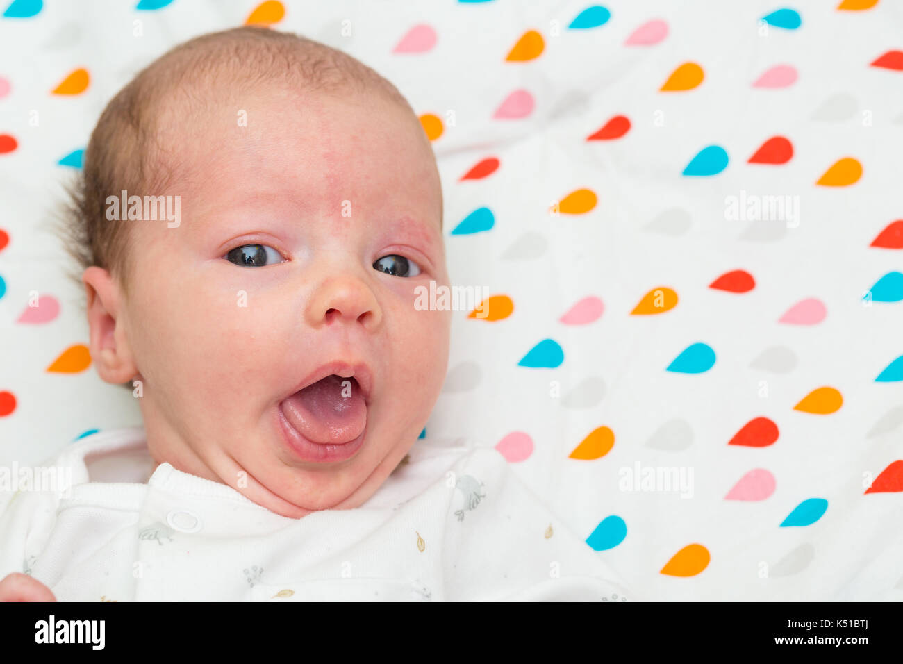 Portrait of a newborn baby looking at the camera with her mouth and eyes wide open Stock Photo