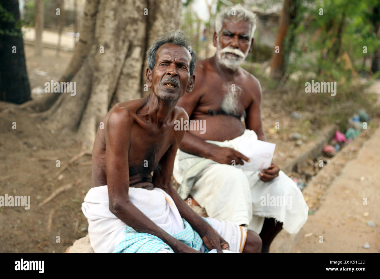 Old man enjoys sitting on a bench. Stock Photo