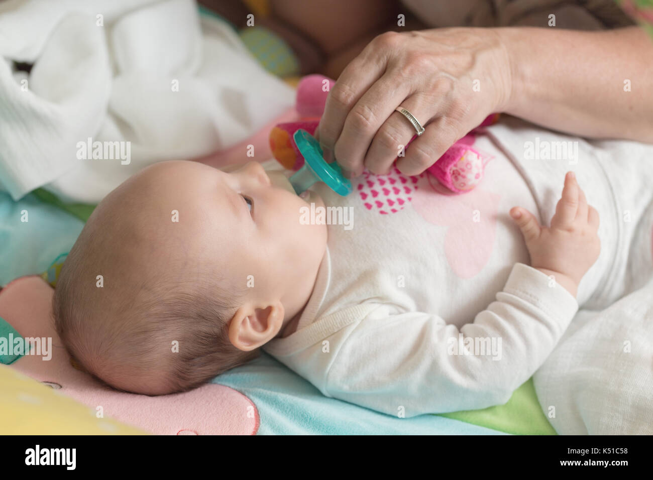 Female hand trying to put a green pacifier into her grandchild's mouth