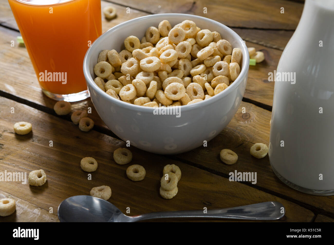 Close-up of cereal rings, orange juice and milk on wooden table Stock Photo