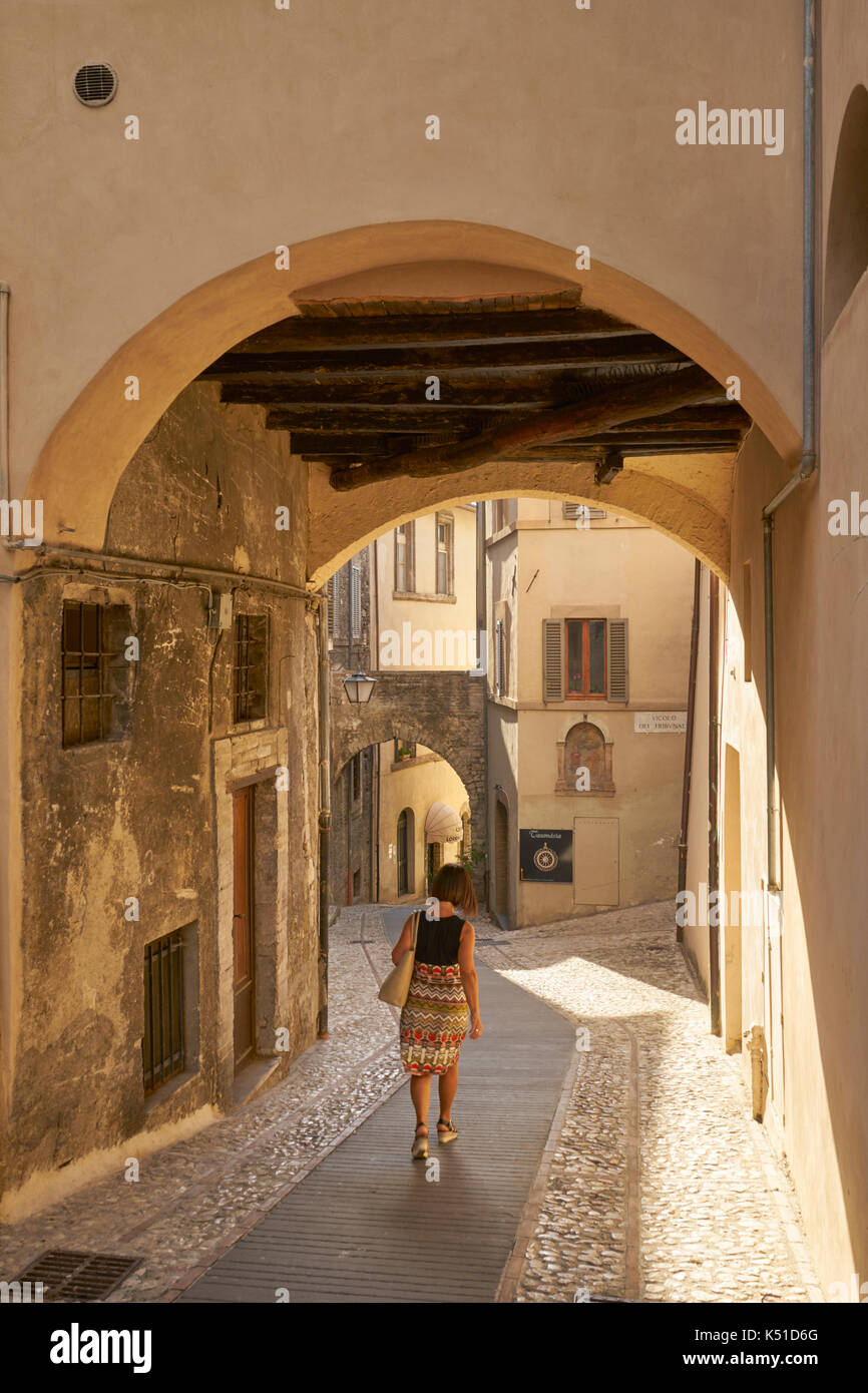 Italian woman walking down narrow arched street, Spoleto, Umbria, Italy Stock Photo