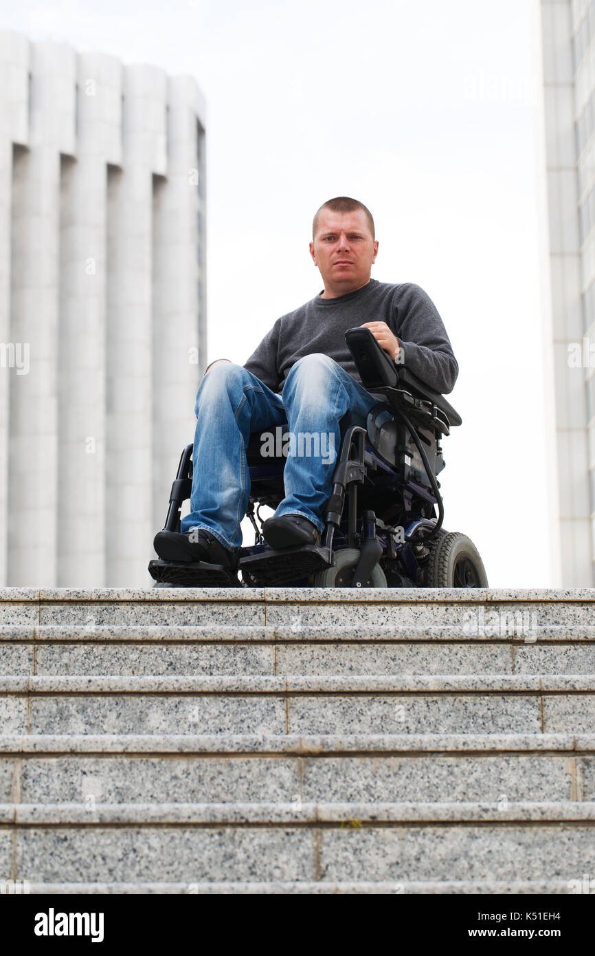 Wheelchair user in front of staircase barrier Stock Photo
