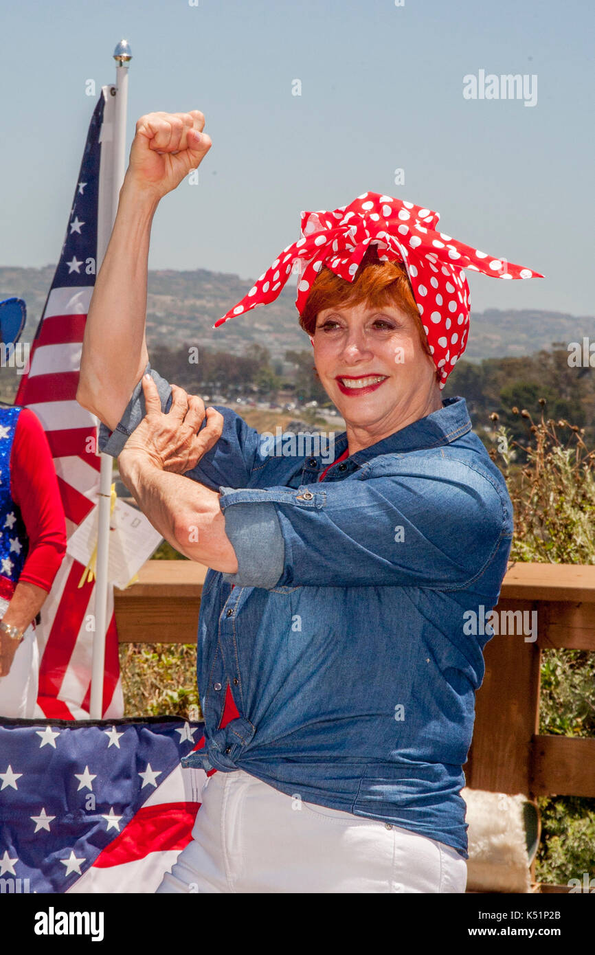 A costumed senior woman reenacts the World War II iconic character Rosie the Riveter at a Fourth of July patriotic ceremony in a Newport Beach, CA, park. Stock Photo