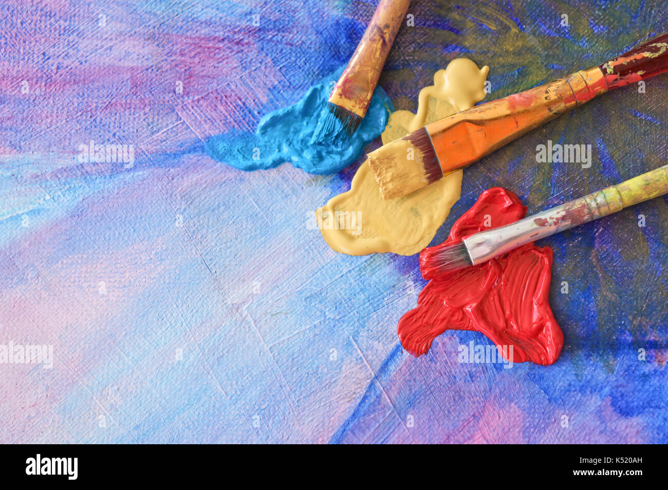 Brushes and colors on painted canvas Stock Photo
