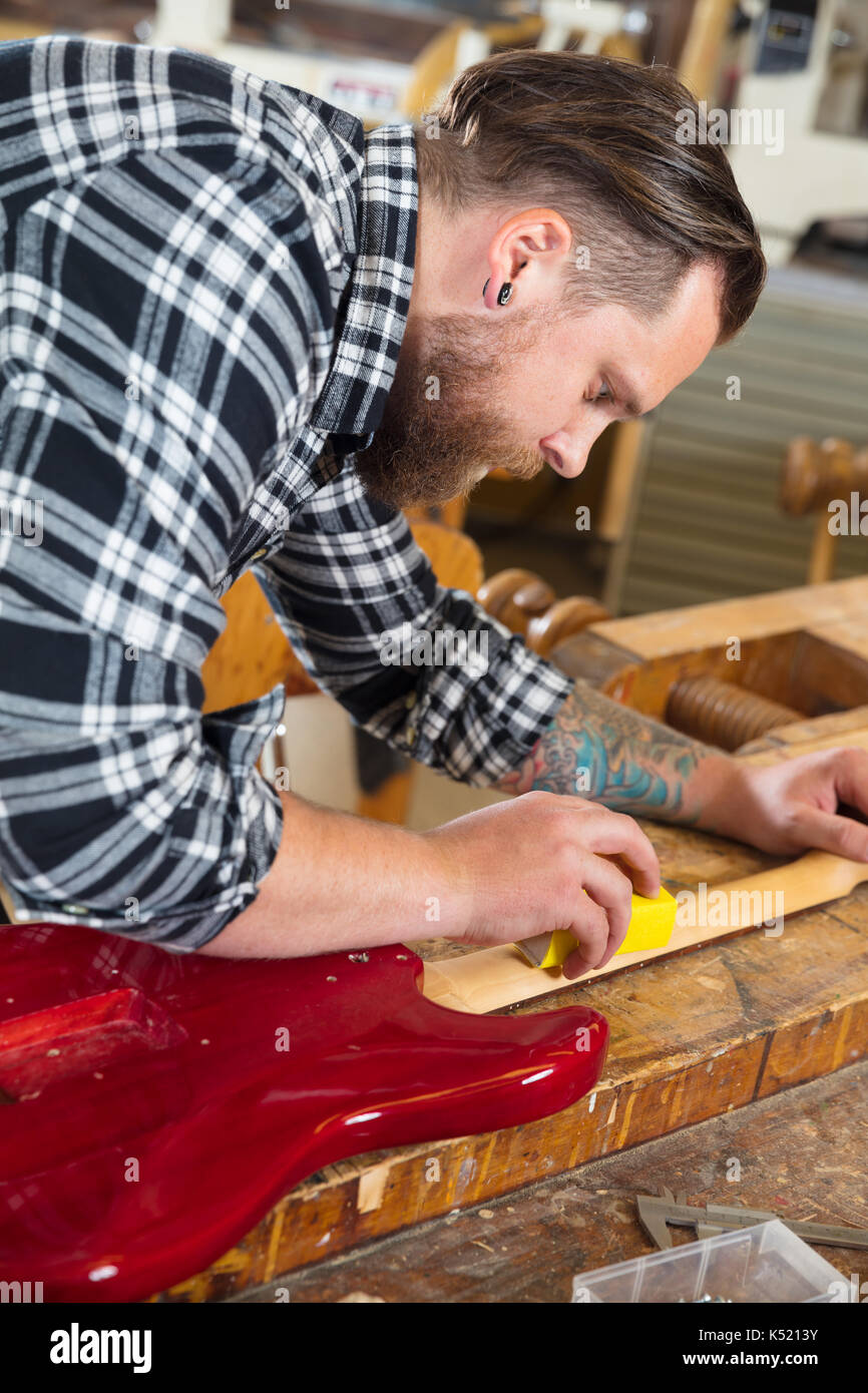 Craftsman sanding a guitar neck in wood at workshop Stock Photo